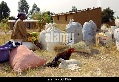 (Afp) - Une femme avec des sacs de charbon et un couple de poulets s'efforce à l'attelage un tour au marché de la ville de Kuito totalement détruits, l'Angola, à environ deux heures d'avion de la capitale, Luanda. Photo prise le 04 septembre, 2003. Dans les dix dernières années jusqu'à ce qu'un cessez-le-feu a été conclu, de violents combats dans et autour de Kuito tué environ un tiers des 500.000 habitants. Les domaines encore aro Banque D'Images