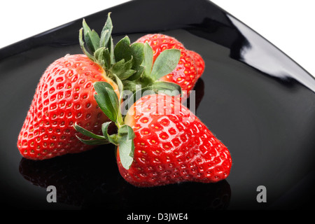 Trois fraises sur soucoupe noire Banque D'Images