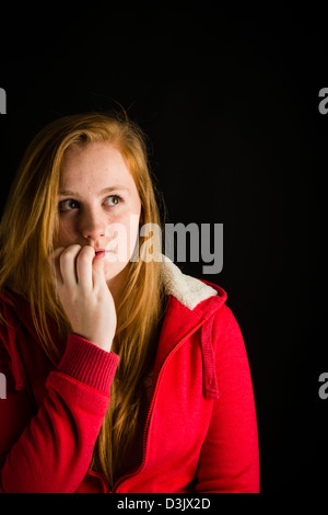 Un timide 16 nerveux, 17 ans, aux cheveux rouges de rousseur face adolescente, mordre ses ongles UK Banque D'Images