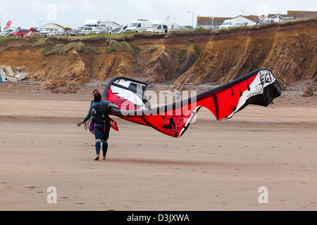 Deux jeunes femmes portent un grand cerf-volant sur la plage de Black Rock, Widemouth Bay nr, Bude, Cornwall, UK Banque D'Images