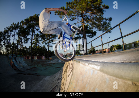 Le BMX rider effectuant un robinet à un tuyau sur un trimestre rampe skatepark. Banque D'Images