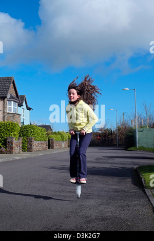 Bouncing Girl Child kid lycéenne sur Pogo Stick Irlande Banque D'Images