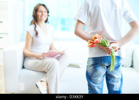 Vue arrière de l' enfant avec bande de magnifiques tulipes derrière retour préparation belle surprise pour sa mère Banque D'Images