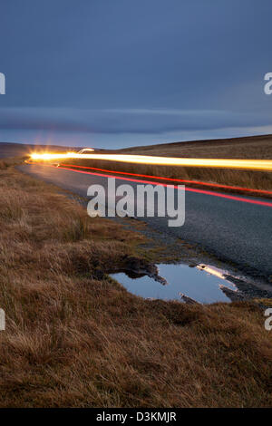 Light trails de voitures passant voyageant le long d'une route dans le Swaledale partie du Yorkshire Dales. Banque D'Images