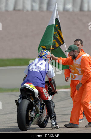 (Afp) - pilote moto allemand Dirk Heidolf obtient un pavillon de Saxe et un jersey de Wismut Aue à partir d'un tracé post après la course de la catégorie 250cc au Sachsenring Hohenstein-Ernstthal près de la piste de course, l'Allemagne, dimanche 31 juillet 2005. Le pilote Honda qui a terminé la course en 13e place provient de Hohenstein-Ernstthal, Allemagne. Photo : Matthias Hiekel Banque D'Images