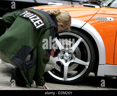 (Afp) - une femme agent de police inspecte l'écoute des pièces de voiture d'une mini à un preview show salon de l'automobile à Essen, en Allemagne, le mardi, 25 octobre 2005. Sous la devise 'tune ! Sécurité !' est la voiture tuning publicité commerciale pour la sécurité des pièces de voiture tuning certifié. La mini voiture compacte rapide peut être vu à l'Essen Motor Show du 25 novembre au 4 décembre 2005. Banque D'Images