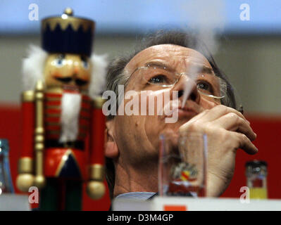 (Afp) - Franz Müntefering, ancien président du Parti Social-démocrate (SPD), souffle la fumée dans l'air comme il est assis à côté d'un Casse-noisette durant la congrès du parti SPD à Karlsruhe, en Allemagne, le mardi 15 novembre 2005. Casse-noisette est un présent de Président nouvellement élu du parti SPD Matthias Platzeck. Photo : Bernd Thissen Banque D'Images