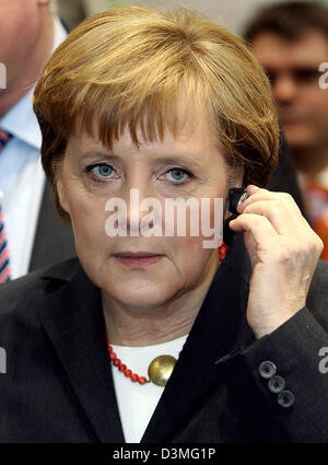 La chancelière allemande, Angela Merkel, casque Bluetooth Motorola tests au salon leader pour l'informatique et de la communication '2006' CeBIT à Hanovre, en Allemagne, le jeudi, 09 mars 2006. Environ 6 300 entreprises de 70 pays vont présenter leurs dernières nouveautés du 9 mars au 15 mars 2006. Photo : Kay Nietfeld Banque D'Images