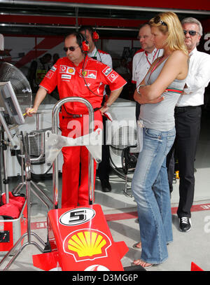 L'ancien médaillé olympique allemand Franziska van Almsick (R) se place en avant d'une voiture, une partie de l'Allemand pilote de Formule 1 Michael Schumacher Ferrari la voiture de course à l'hippodrome de Formule 1 près de Manama, Bahreïn, le vendredi 10 mars 2006. La première course du championnat du monde de F1 2006, le Grand Prix de Bahreïn, aura lieu ici le dimanche 12 mars 2006. Photo : Carmen Jaspersen Banque D'Images