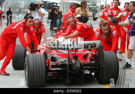 (Dpa) - Mécanique repousser la voiture de l'Allemand Michael Schumacher, pilote de Formule 1 de la Scuderia Ferrari Marlboro F1 Team au cours de la troisième session d'essais à la course de Formule 1 près de Manama, Bahreïn, le 11 mars 2006. La première course du championnat du monde de F1 2006, le Grand Prix de Bahreïn, aura lieu ici le 12 mars 2006. Photo : Carmen Jaspersen Banque D'Images