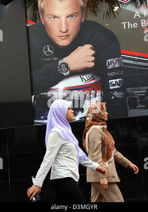 Deux femmes passent une affiche publicitaire montrant le pilote de formule 1 finlandais Kimi Raikkonen de McLaren Mercedes au centre-ville de Kuala Lumpur, Malaisie, le mercredi, 15 mars 2006. Le Grand Prix de Malaisie 2006 prend ici place à Sepang 19 mars 2006. Photo : Jens Buettner Banque D'Images