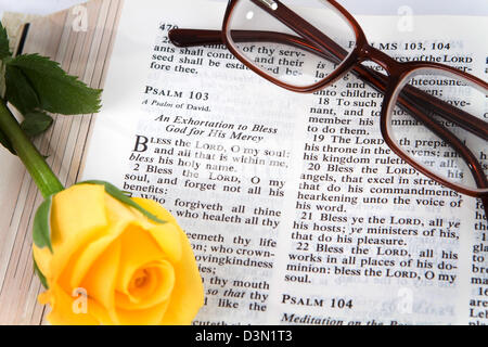 Sainte Bible ouverte pour le livre des Psaumes chapitre 103 avec une rose jaune et lunettes de lecture. Banque D'Images