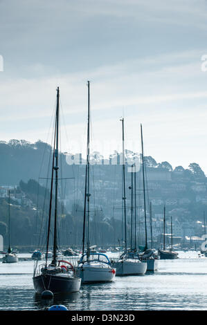 La voile bateaux amarrés dans une ligne sur une rivière calme et toujours à la Dart vers Kingswear sur un ton gris et bleu matin Banque D'Images