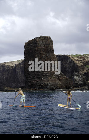 Un jeune couple sur le stand-up paddle boards à aiguilles à l'extérieur de l'île de Lanai, Hawaii. Les deux sont libérés du modèle. Banque D'Images