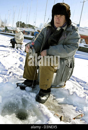 Un homme poissons au port dans la banlieue de Tallinn, capitale de l'Estonie, 24 mars 2006. La pêche sur glace est un passe-temps populaire en Estonie au cours de l'hiver. Photo : Andreas Gebert Banque D'Images