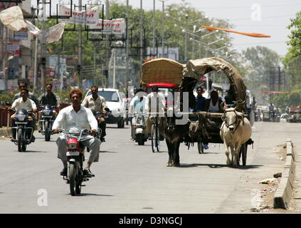 La photo montre un véhicule semble archaïque tiré par un bœuf de moderne des scooters et des voitures sur une route à Indore, Inde, 28 avril 2006. Indore réside dans l'état fédéral de Madhya Pradesh et compte 1.692.400 millions d'habitants. C'est une ville industrielle avec du coton, Metall, des meubles et de l'industrie chimique, un centre culturel avec une université, théâtres, musées, cinémas et un scien Banque D'Images