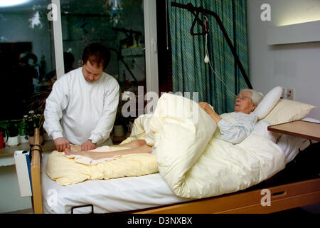 (Afp) un aide-soignant pour les personnes âgées montré au cours d'une séance de physiothérapie avec une femme de 97 ans au lit à l'Erna-David-Seniorenzentrum' à Dortmund, en Allemagne, le 11 mars 2005. Photo : Klaus Rose Banque D'Images