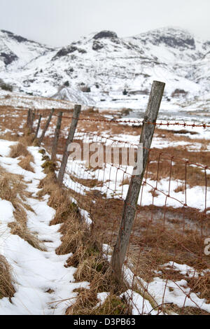 Vieille clôture en fil barbelé Coniston Copper Mines en hiver avec la neige sur les collines, Lake District, UK Banque D'Images