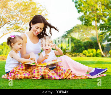 Photo de belle femme avec la fille et le fils de s'asseoir et lire, de fées Banque D'Images