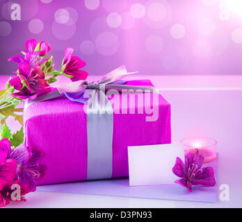 Photo de rose boîte cadeau de luxe avec bouquet de fleurs magnifiques, dîner romantique aux chandelles et une carte postale avec le texte de l'espace sur la table Banque D'Images