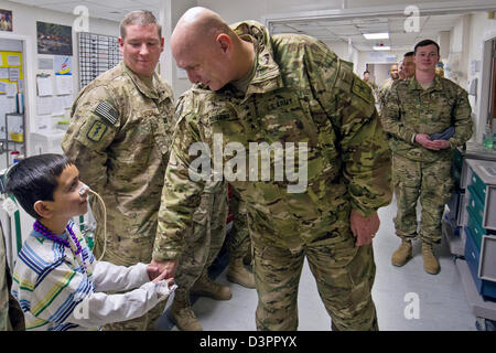 Le général américain Raymond Odierno, le chef du personnel de l'Armée secoue la main d'un enfant afghan se redresser à la Le s.. Heather N. Craig de l'hôpital interarmées de théâtre 21 février 2013 à l'aérodrome de Bagram, en Afghanistan. Banque D'Images