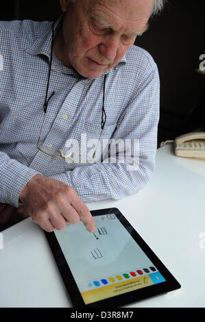 75 ans Grand-père jouant tirer quelque chose contre son petit-fils de l'app sur l'Ipad. Banque D'Images