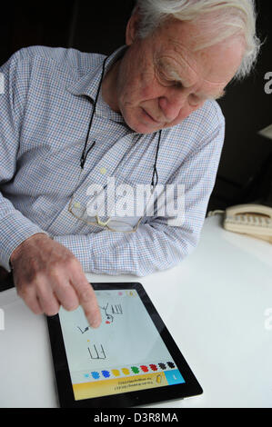 75 ans Grand-père jouant tirer quelque chose contre son petit-fils de l'app sur l'Ipad. Banque D'Images