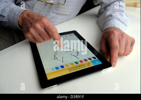 75 ans Grand-père jouant tirer quelque chose contre son petit-fils de l'app sur l'Ipad. Banque D'Images