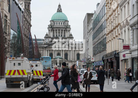 Belfast, Royaume-Uni. 23 février 2013. Exploitation d'acheteurs quel que soit le drapeau de l'Union malgré les manifestations devant l'hôtel de ville de Belfast. Les manifestations de rue ont eu lieu depuis le 3 décembre, lors du Conseil de la ville de Belfast a voté pour réduire le nombre de jours de l'Union européenne drapeau est hissé à l'Hôtel de Ville. La manifestation était organisée simultanément avec une parade marquant le 25e anniversaire de l'Ulster Defence Regiment deux hommes tués par une bombe de l'IRA en 1988. Credit : Lee Thomas / Alamy Live News Banque D'Images