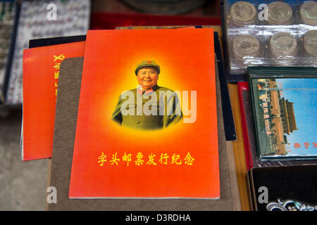 Un livre de poche rouge portant une photo du président Mao est assis sur une table entre des antiquités à un marché d'antiquités à Hong Kong. Banque D'Images