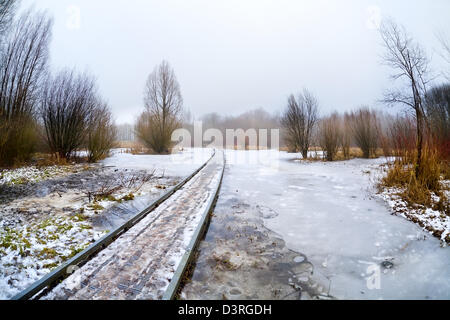 Pont routier en bois par lac gelé en jour brumeux Banque D'Images