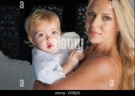 Maman mère maman est titulaire d'enfant dans ses bras, tous deux bien à l'apprentissage et l'enseignement de l'innocence de l'appareil photo concentration Banque D'Images