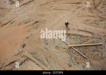 Homme marchant dans la boue à la mine Kansanshi Banque D'Images