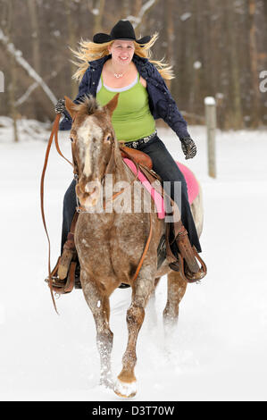 Femme cheval Appaloosa Horse in snowy field, blond twentysomething portant chapeau de cow-boy noir, l'hiver à New York, PA, USA. Banque D'Images