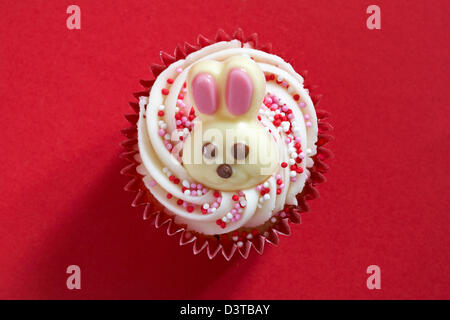 Cupcake de Pâques au chocolat blanc lapin sur isolé sur fond rouge Banque D'Images