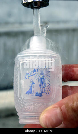 Un pèlerin se remplit de l'eau de source dans une petite bouteille marquée avec une vierge dans le lieu de pèlerinage Lourdes, France, 08 septembre 2006. Vierge Marie est dit avoir plusieurs fois appered à 14 ans, Bernadette Soubirous à la grotte de Massabiell à compter du 11 février 1858. Au cours d'une de ces visions Bernadette exposés une source, qui est considéré comme ayant des pouvoirs de guérison. Photo : Banque D'Images