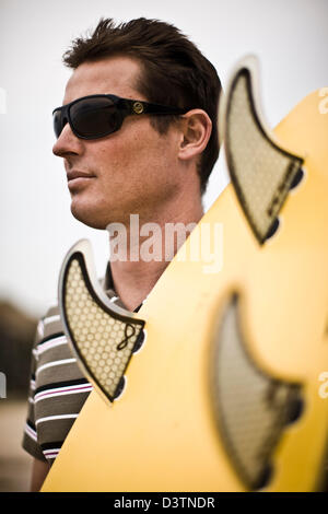 Surfer dans les tons se dresse face à la mer, Sainte Agnès, Cornwall, UK Banque D'Images
