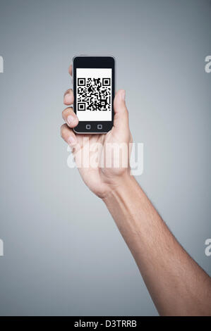 Les personnes hand holding a mobile phone avec code-barres 2D sur l'écran Banque D'Images
