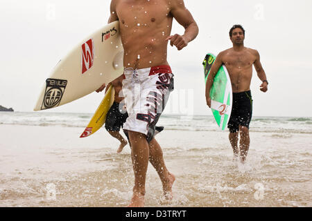 Les surfeurs s'exécutant dans la mer froide, St Agnes, Cornwall, UK Banque D'Images