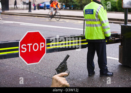 Barrières de police mis en place autour de la Maison du Parlement à Londres à l'abri de véhicule ou les kamikazes, et une arme à la main. Banque D'Images