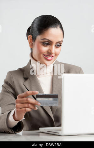 Businesswoman holding d'une carte de crédit et l'aide d'un ordinateur portable Banque D'Images