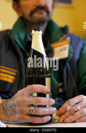 Le vendeur d'un sans-abri' Newspaper est titulaire d'une bouteille de bière dans la main droite et une cigarette dans sa main gauche à Nuremberg, Allemagne, jeudi, 14 décembre 2006. Photo : Daniel Karmann Banque D'Images