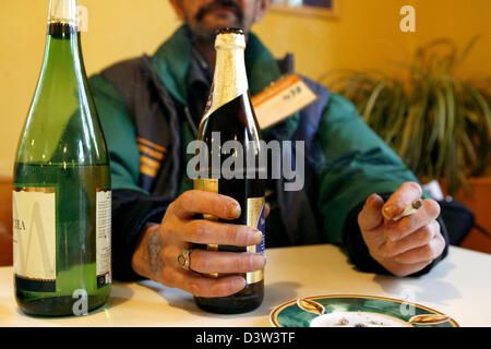 Le vendeur d'un sans-abri' Newspaper est titulaire d'une bouteille de porter dans sa main droite et une cigarette dans sa main gauche à côté d'une bouteille de vin blanc à Nuremberg, Allemagne, jeudi, 14 décembre 2006. Photo : Daniel Karmann Banque D'Images