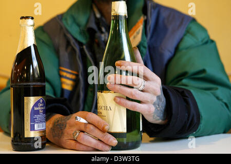 Le vendeur d'un sans-abri' Newspaper est titulaire d'une bouteille de vin blanc dans sa main gauche et une cigarette dans la main droite à côté d'une bouteille de bière à Nuremberg, Allemagne, jeudi, 14 décembre 2006. Photo : Daniel Karmann Banque D'Images