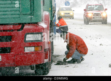 Les chauffeurs de camions monter les chaînes à neige pour les pneus de leur camion sur l'autoroute B31 en Hoellental, Allemagne, mercredi, 24 janvier 2007. De fortes chutes de neige pendant la nuit a créé des situations de trafic chaotique dans les régions du sud de l'Allemagne. Photo : Patrick Seeger Banque D'Images