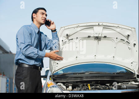 Bengali man a broken down car et de parler sur un téléphone mobile Banque D'Images