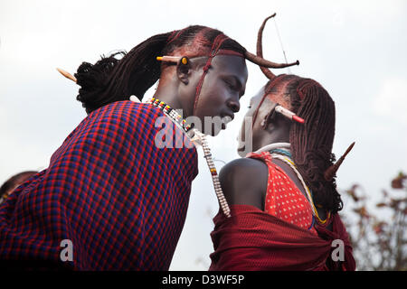 Les jeunes hommes massaï rouge avec des perles, des shukas et cheveux tressés la traditionnelle danse Danse jump adumu lors d'une fête de mariage. Banque D'Images