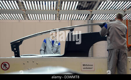 Deux employés de Volkswagen prendre parties latérales pour un Golf VII à partir de la ligne de production à la presse boutique dans le tunnel de lumière pour l'inspection finale à l'usine VW de Wolfsburg, Allemagne, 25 février 2013. Photo : JOCHEN LUEBKE Banque D'Images