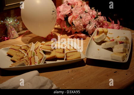 Couper le gâteau de mariage et présenté sur une plaque avec un ballon et bouquet. Banque D'Images