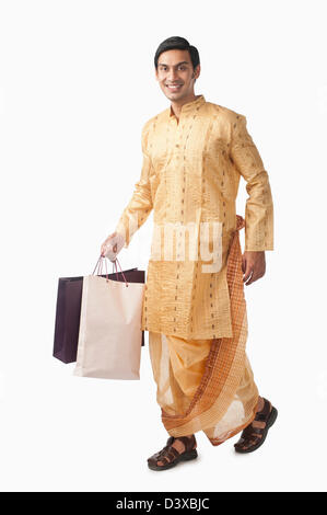 Bengali man carrying shopping bags and smiling Banque D'Images